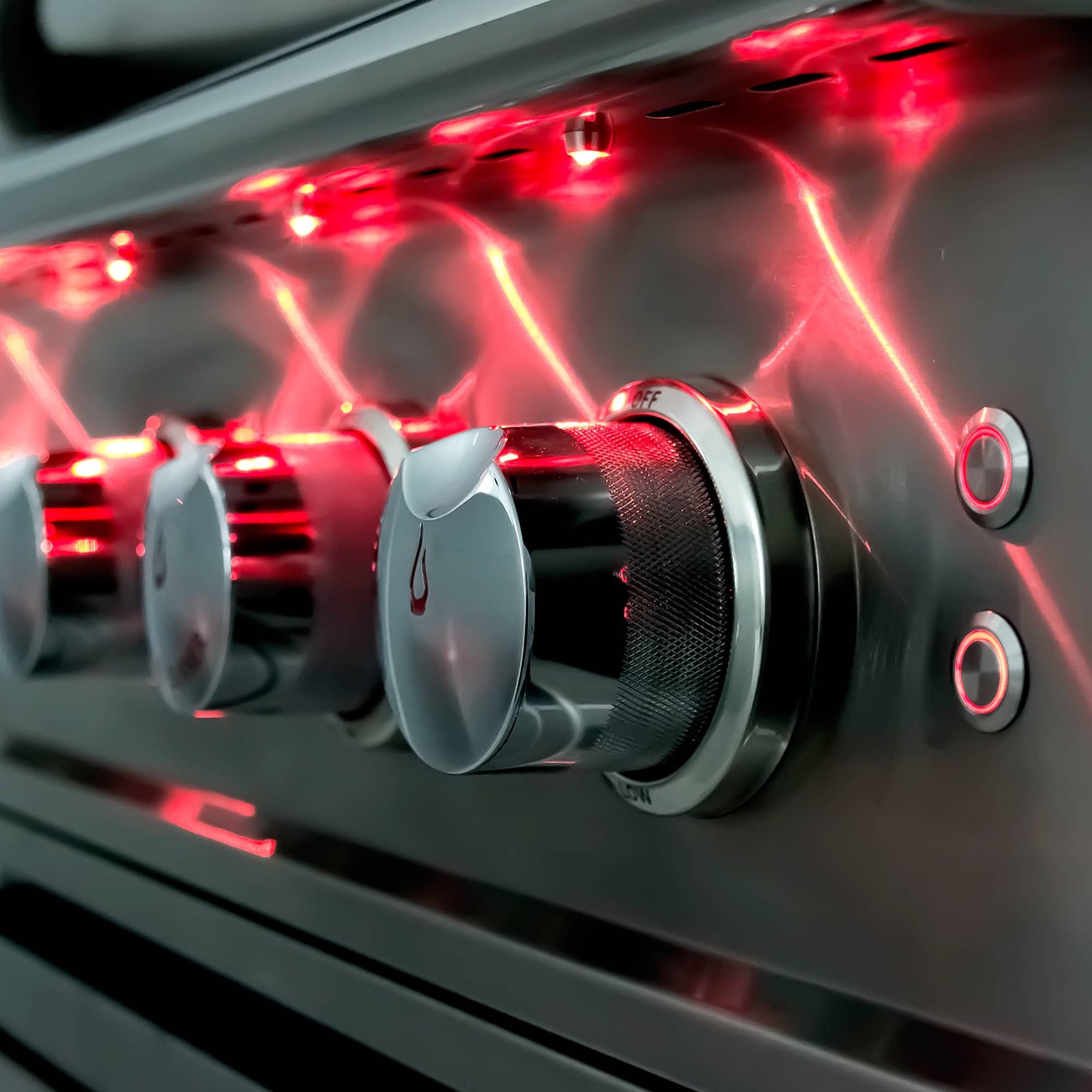 The red LED-lit control knobs on a Blaze gas grill, with the Blaze flame mark on the knob
