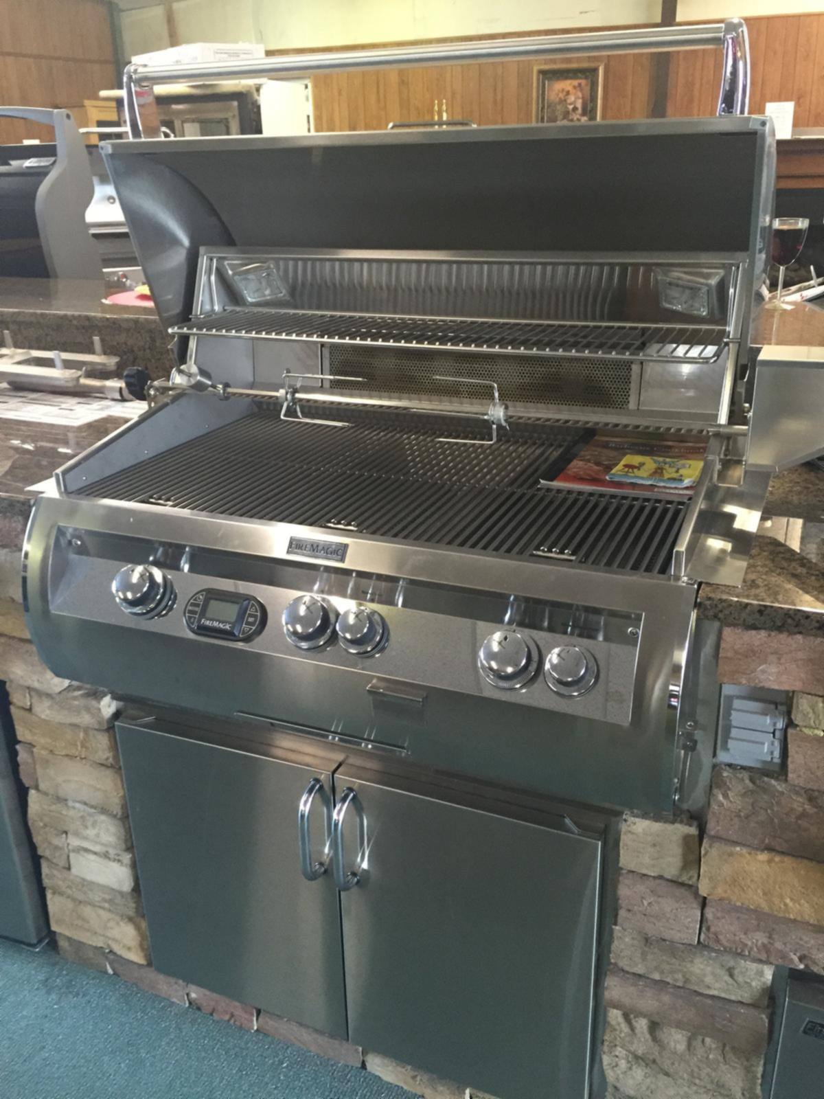 A stainless built-in gas grill set into a stone outdoor kitchen surround in our showroom