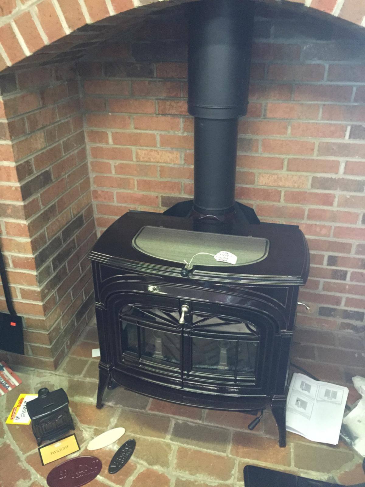 A black cast iron freestanding stove set in a brick alcove