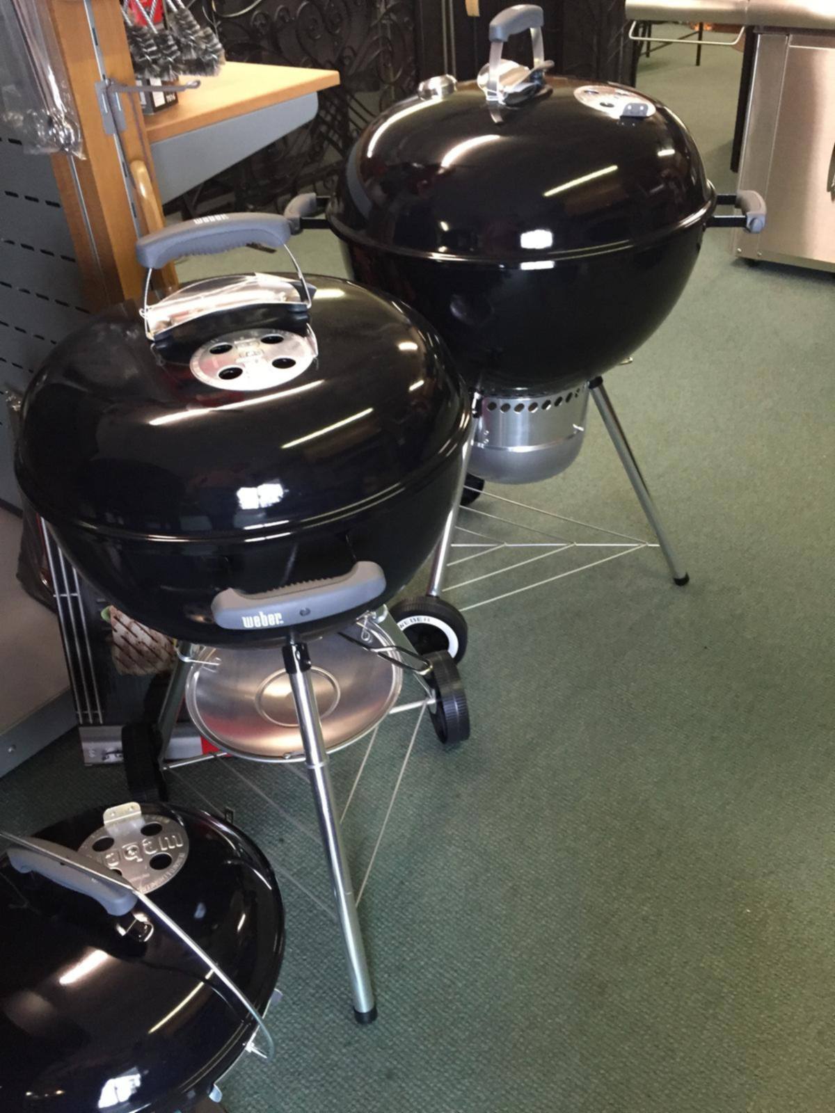 Two black charcoal kettle grills on our showroom floor
