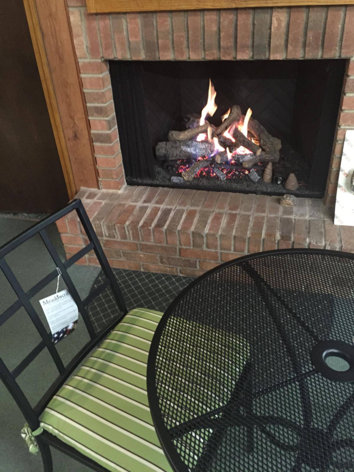 A gas log set burning in a brick fireplace