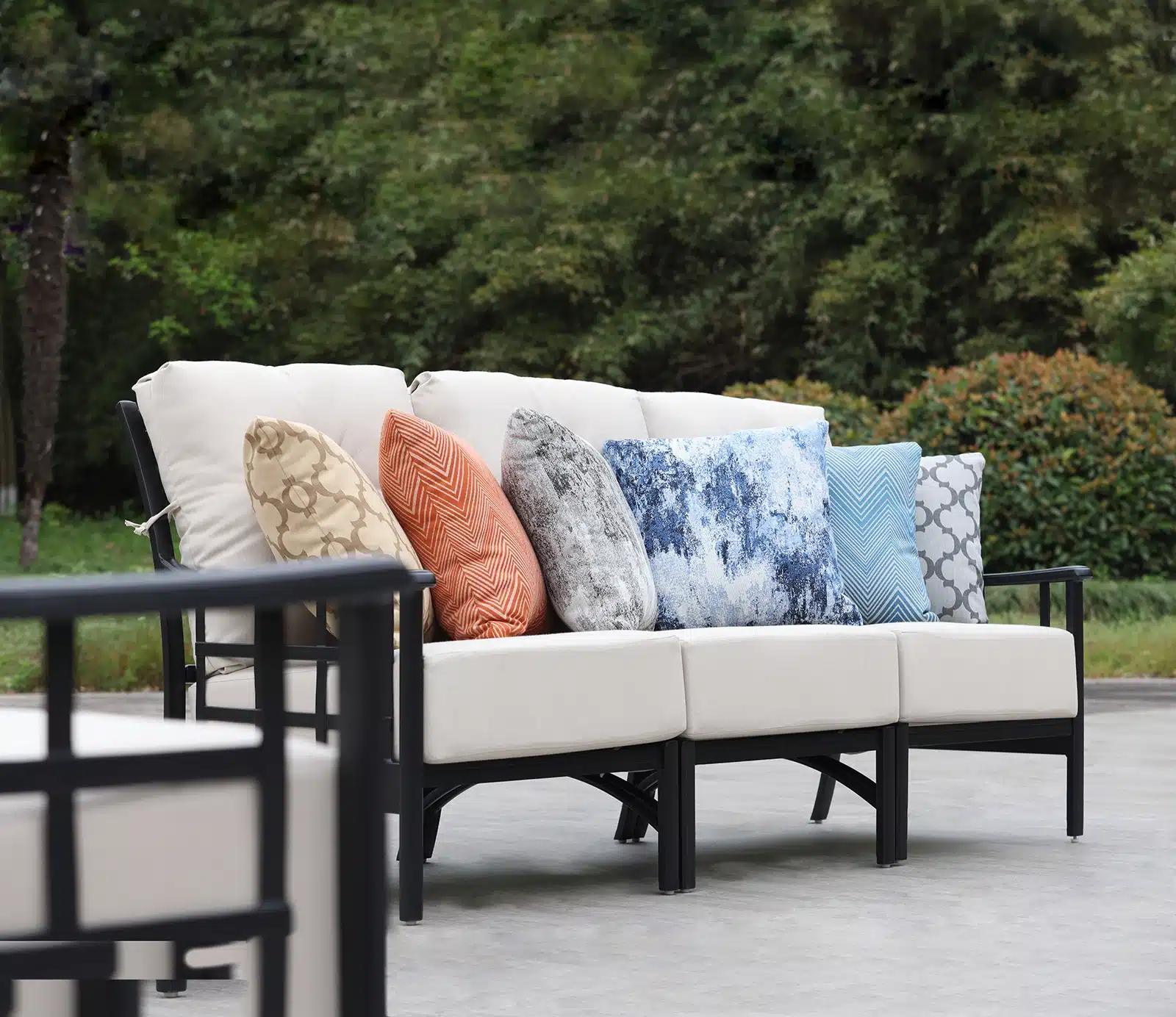 A Hanamint sofa lined with six throw pillows, each in a different outdoor fabric