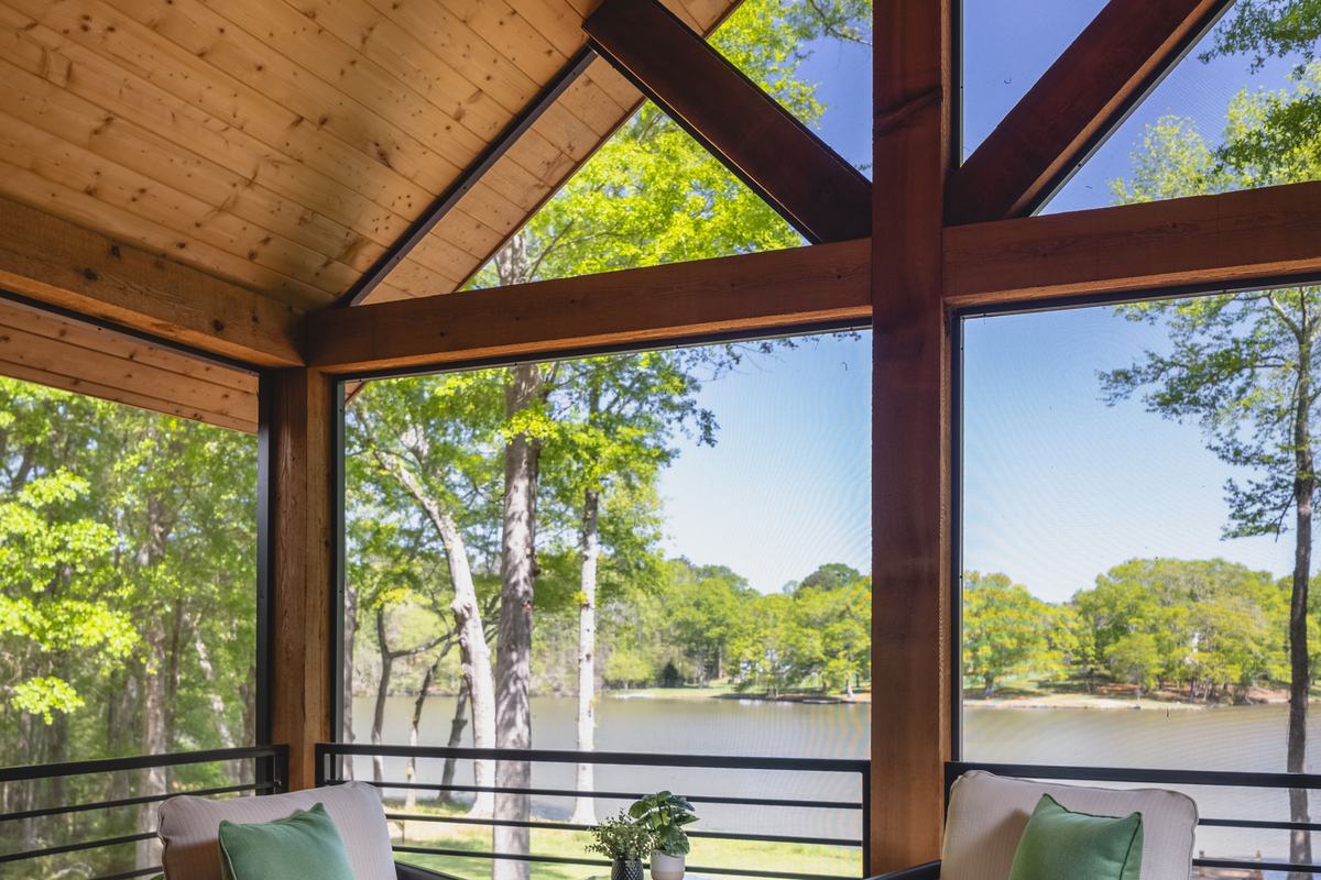Two Lloyd Flanders Galloway rockers with green pillows on a screened porch overlooking a lake